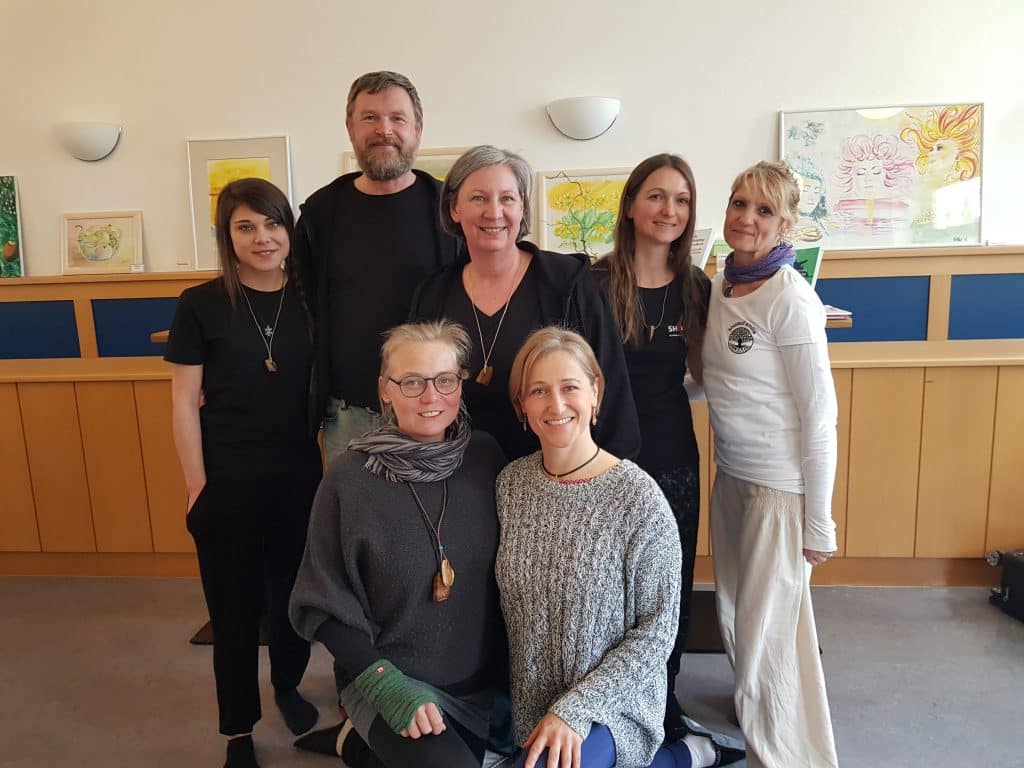 Gruppe von Personen posiert in einem Raum mit Kunstwerken, geeignet für Shiatsu-Kurse oder Behandlungen.