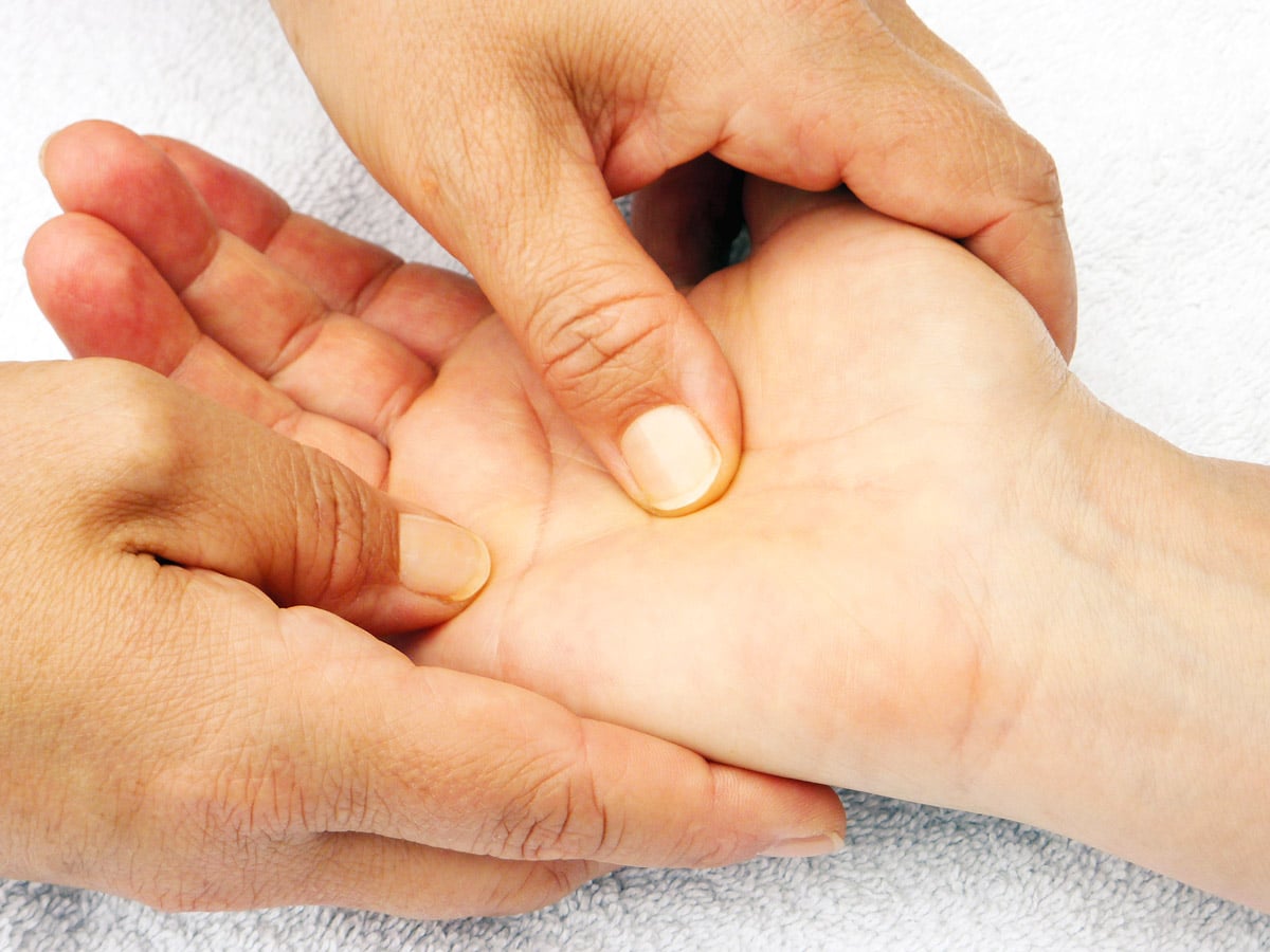 Hand wird bei einer Shiatsu-Behandlung massiert, Fokus auf Drucktechnik.
