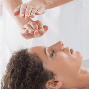 Person erhält Shiatsu-Behandlung, Hände schweben über dem Gesicht für Entspannung und Stressabbau.