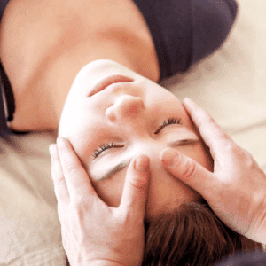 Person erhält entspannende Shiatsu-Behandlung, Hände massieren sanft ihren Kopf für Entspannung und Wohlbefinden.