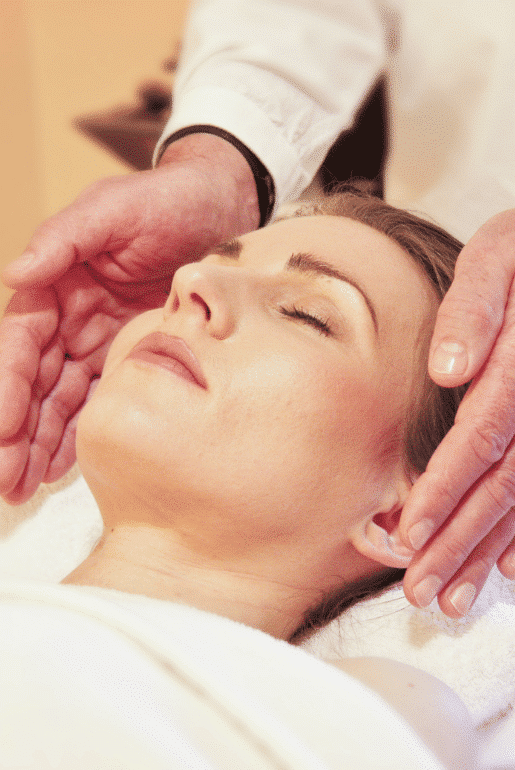 Person genießt Shiatsu-Behandlung, zwei Hände nahe Gesicht, entspannende Wellness-Atmosphäre.