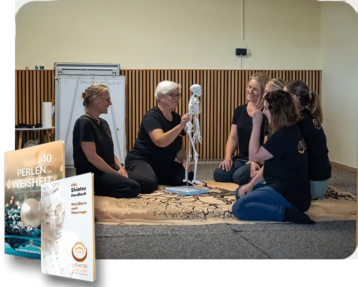 Personengruppe bei Shiatsu-Kurs, lernen mit Skelettmodell. Bücher Perlen der Weisheit und Shiatsu Handbuch im Vordergrund.