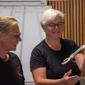 Zwei Personen betrachten ein menschliches Skelettmodell bei einem Shiatsu-Kurs in einem Schulungsraum.