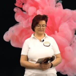Person in Shiatsu-Uniform liest in einem Buch, vor einem Hintergrund aus rosa Rauchwolken.