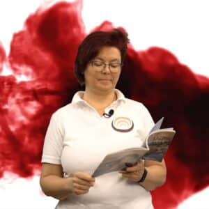 Person in weißem Polohemd mit Logo liest ein Buch vor einem rot-schwarzen Hintergrund, das Shiatsu thematisiert.