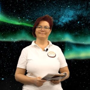 Eine Person in weißem Polohemd präsentiert ein Buch vor einem Hintergrund mit Nordlichtern und Sternenhimmel.